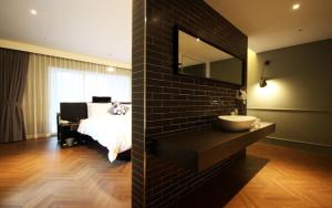 a bedroom with a bed and a sink and a mirror at Ulsan Samsan Pandora Hotel in Ulsan