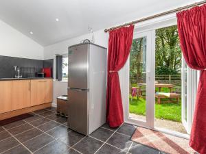a kitchen with red curtains and a refrigerator at Cwtch Lloi - Qc1665 in Llandeloy