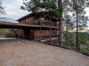 a large wooden cabin with a balcony in the trees at Enchanted Oak Cabin in Ruidoso