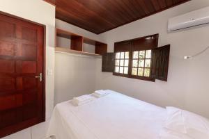 um quarto com uma cama com lençóis brancos e uma janela em Residencial Maragogi em Maragogi