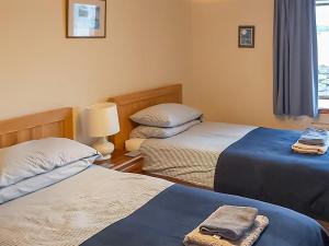 a bedroom with two beds and a lamp and a window at Ben View in Gairloch