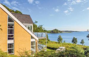 uma casa de tijolos com vista para uma massa de água em Amazing Home In Krus With 3 Bedrooms, Sauna And Wifi em Rønsheved