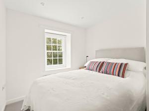 a white bedroom with a white bed with a window at Croft Y Beudy in Henfynyw Upper