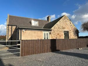 a detached house with a wooden fence in front of it at Prior House Farm in Berwick-Upon-Tweed