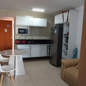 a kitchen with a stainless steel refrigerator and a table at Praia dos Carneiros Flat Hotel Lindo Apto 302 in Praia dos Carneiros