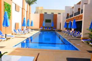 een zwembad met stoelen en blauwe parasols bij Moon Light Hotel Cairo DAR EL ESHARA in Caïro