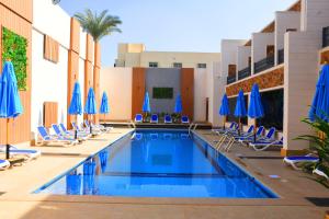 einen Pool mit Stühlen und blauen Sonnenschirmen in der Unterkunft Moon Light Hotel Cairo DAR EL ESHARA in Kairo
