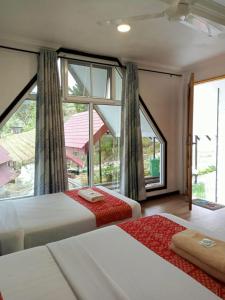 two beds in a room with a large window at KUNDASANG MOUNT GARDEN in Kampong Kundassan