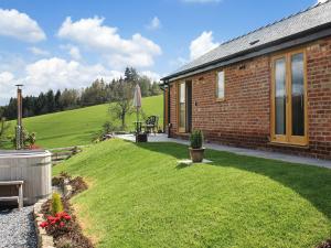 a small brick house with a grass yard at Megs Rest in Bettws Cedewain