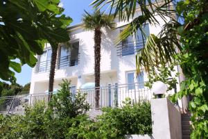 a white house with palm trees in front of it at Apartments Palma in Šibenik