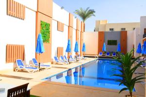 カイロにあるMoon Light Hotel Cairo DAR EL ESHARAのホテル内のスイミングプール(椅子、パラソル付)