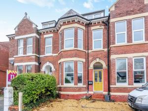 a red brick house with a yellow door at Apartment Two - Uk45353 in Southport