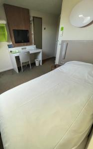 1 dormitorio con 1 cama blanca grande y escritorio en Campanile Dunkerque Sud - Loon Plage en Loon-Plage