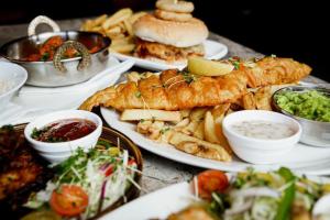uma mesa coberta com pratos de comida com peixe e batatas fritas em Lomond Park Hotel em Balloch
