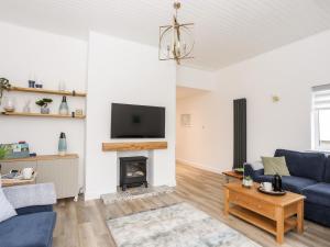 a living room with a blue couch and a fireplace at Llwyn Eithin in Holyhead