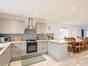 a kitchen with white cabinets and a dining room with a table at Llwyn Eithin in Holyhead