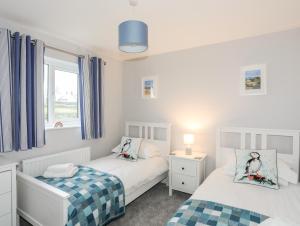 two twin beds in a bedroom with a window at Llwyn Eithin in Holyhead