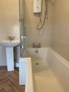 a bathroom with a shower and a tub and a sink at Old Hundred View in Tormarton
