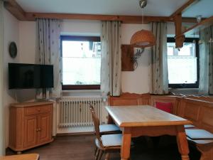 a dining room with a table and a tv at Auszeitstube - Chiemgau Karte in Inzell