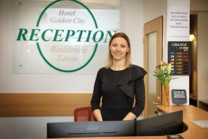 a woman standing in front of a reception desk at Hotel Golden City Garni in Prague