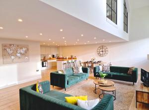 sala de estar con sofás verdes y cocina en The Academy House by Bevolve, en Shrewsbury