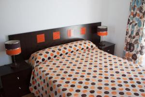1 cama con edredón naranja y negro y 2 lámparas en Apartamentos Muro, Juana & Charca, en Conil de la Frontera