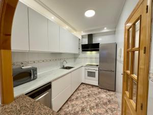 eine Küche mit weißen Schränken und einem Kühlschrank aus Edelstahl in der Unterkunft Modern Apartment On Playa Del Cura in Torrevieja