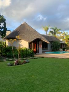 a house with a thatched roof and a yard at Mountain Dew Guest House in George