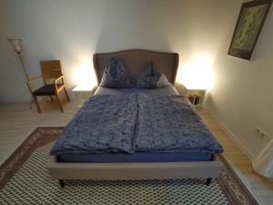 a bedroom with a bed with a blue comforter and a chair at Balingen Apartment in Balingen
