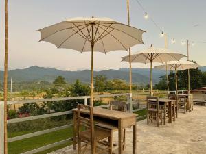 een groep tafels met parasols op een patio bij Nadoiview Homestay นาดอยวิวโฮมสเตย์ in Pua +20 foto's