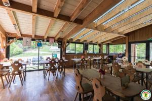 un restaurant avec des plafonds en bois, des tables et des chaises dans l'établissement Auberge La Soulan, à Boutx