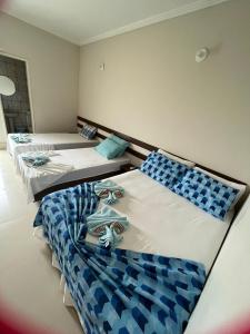 trzy łóżka w pokoju niebiesko-białym w obiekcie APARTAMENTO 104- BGMC w mieście Guaibim