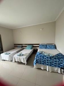 a room with two beds with blue and white sheets at APARTAMENTO 104- BGMC in Guaibim