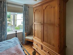 um armário de madeira num quarto com uma janela em Hillview Cottage em North Nibley