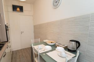 a kitchen with a table with chairs and a clock on the wall at ALBA APARTMENT near MILAN in Bresso