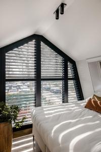 1 dormitorio con cama blanca y ventana grande en Lovely private cottage near Amsterdam en Broek in Waterland