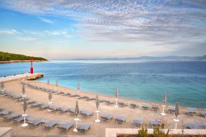 a group of chairs and umbrellas on a beach at Grand Hotel View in Postira