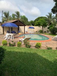 einen Pool mit Stühlen und Sonnenschirmen im Hof in der Unterkunft Tilo Lodge in Banjul