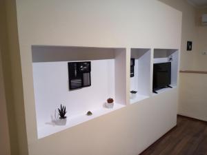 a room with a white wall with a tv and plants at Green Corner Wellness in Püspökladány +60 photos