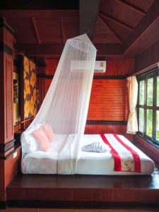 a bed with a mosquito net in a room at Baan Laanta Resort & Spa - SHA PLUS in Ko Lanta