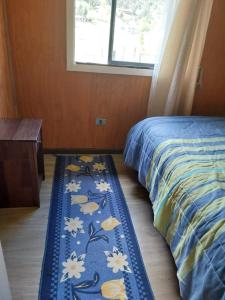 a bedroom with a bed and a rug on the floor at Cabaña lancuyen in Futrono