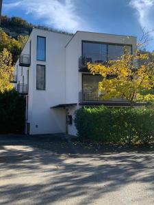une maison blanche avec un arbre en face dans l'établissement Motel by Maier Feldkirch - kontaktloser Check-in, à Feldkirch