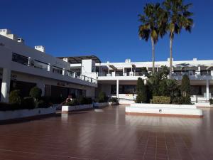 un gran edificio blanco con palmeras delante en Casa ARCO IRIS avec Jardin et Terrasse - piscine et jacuzzi partagés - by Cathy Ducoin en San Juan de los Terreros