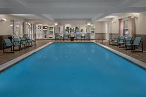 a pool in a hotel with chairs and tables at Residence Inn East Rutherford Meadowlands in East Rutherford