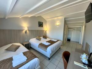 una camera d'albergo con due letti e un tavolo di Hôtel Les Arcades a Saintes-Maries-de-la-Mer