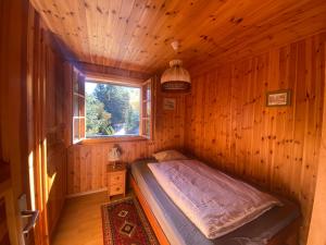 a bed in a wooden room with a window at Chalet Rustique à La Tzoum' in La Tzoumaz
