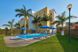 a pool with chairs and umbrellas in front of a building at City Express by Marriott Lazaro Cardenas in Lázaro Cárdenas