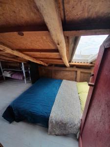 Cama en habitación con techo de madera en Lobo Hostel Bar, en Cabo Polonio