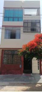 un edificio con un árbol de flores rojas delante de él en Departamento-Bolognesi B1, en Chiclayo