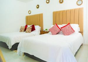um quarto com 2 camas com almofadas vermelhas e brancas em Hotel Bungalows Casa Blanca em Tenancingo de Degollado